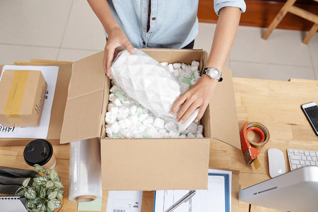 Person packing a box with bubble wrap on a desk